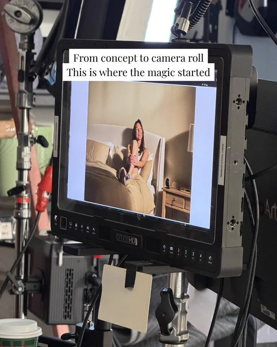 A monitor on a film set shows an image of a woman sitting on a bed. The overlay text reads 'From concept to camera roll, this is where the magic started.'