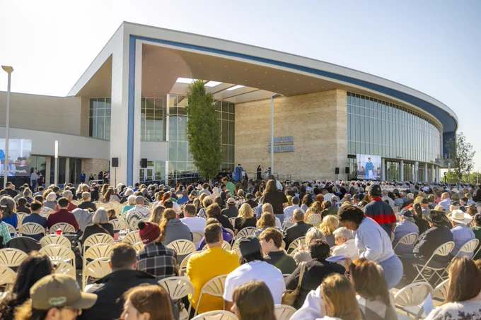 Photo from behind the crowd of guests and seated graduates. 