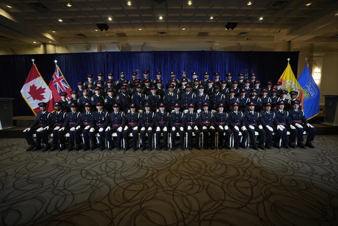 Group picture of uniformed members posing in front of blue blackground