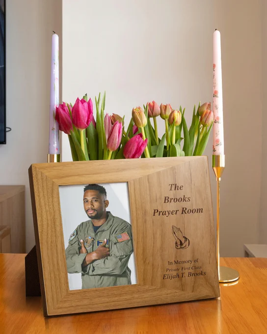 Red Alder Picture Frame With Soldier Photo And Engraved With Memorial And Hands In Prayer Art On Table By Candles And Flowers