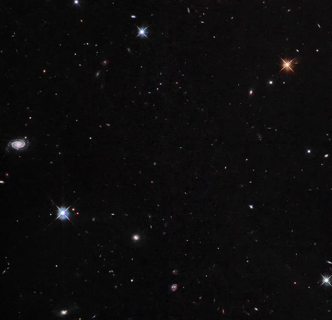 Several bright stars and many background galaxies are visible against a black background.