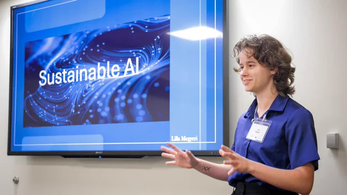 Person in blue shirt presenting a slide titled 'Sustainable AI' on a large screen.