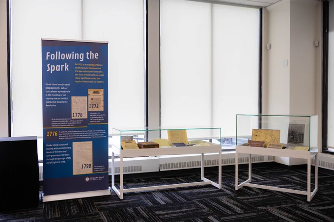 Museum banner with title "Following the spark" beside two display cases with documents inside.