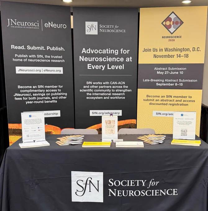 A booth display featuring the Society for Neuroscience with information on membership benefits and upcoming events. The setting is professional and informative.