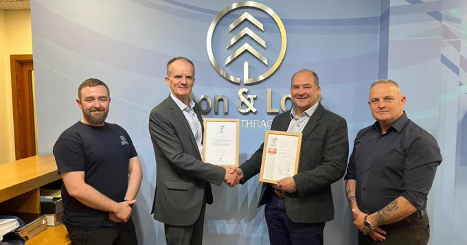 Don & Low's Managing Director holding an Armed Forces Covenant certificate and Highland RFCA's Defence Relationship Manager holding an Employer Recognition Scheme Bronze Award certificate in-between two employees.