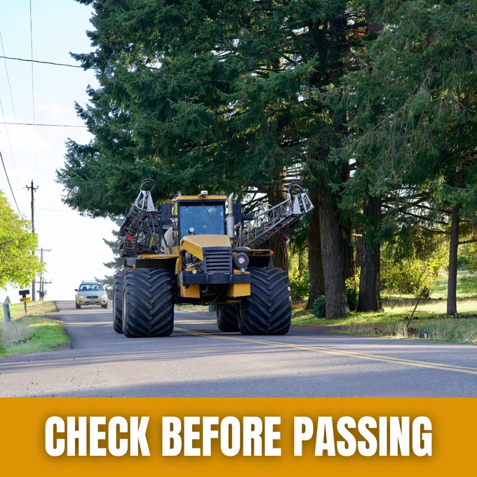Image of a large agricultural machine with wide tires traveling on a rural road. A car is visible in the background behind the tractor.
The text overlay at the bottom reads, Check Before Passing.