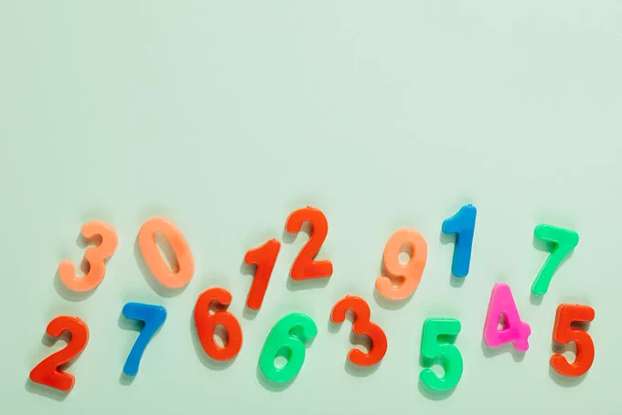 Bright plastic numbers on a mint green background for learning and education.