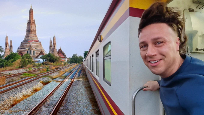 Michael Downie, holding onto the train car with windswept hair, is on a train through Bangkok.