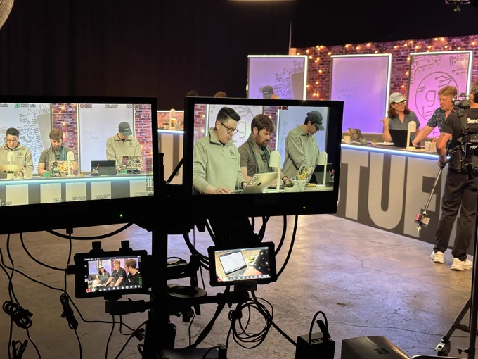 monitors showing 4 camera angles in front of the set where were filming. tags of three are on laptops at their desks