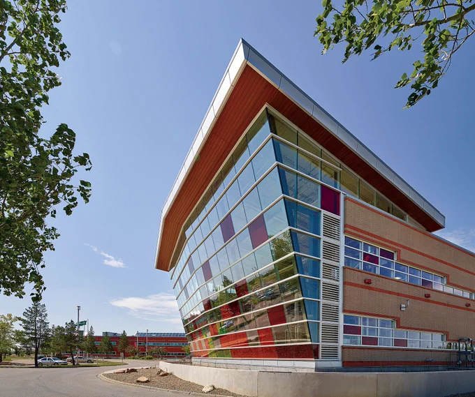 a building on the Lakeland College Lloydminster campus made of glass with a red roof and alternating clear and red glass tiles. 