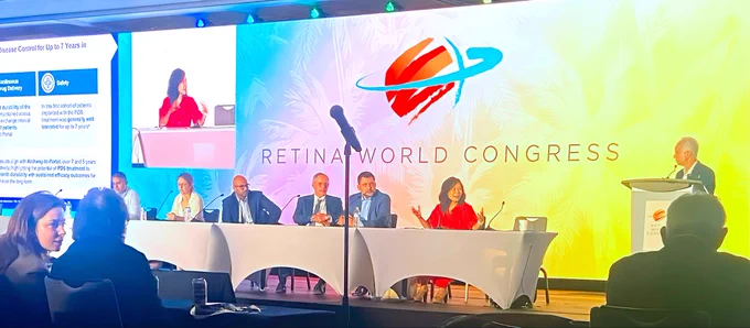 Woman speaking at table with Retina World Congress backdrop