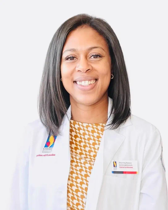 A person smiling wearing a white coat with a PCOM Georgia logo on the chest.