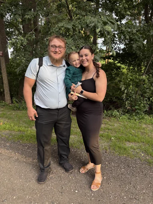 Becca holding her daughter, standing next to her fiance outdoors