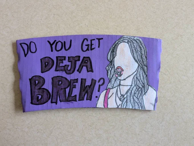Hand-drawn artwork on a purple cardboard Starbucks cup sleeve resting on a light textured surface. The left side features bold, stylized text outlined in black that reads, "DO YOU GET DEJA BREW?". The right side features a color-pencil sketch of a young woman with long dark hair, wearing a white top and necklace, holding a round lollipop in her mouth.