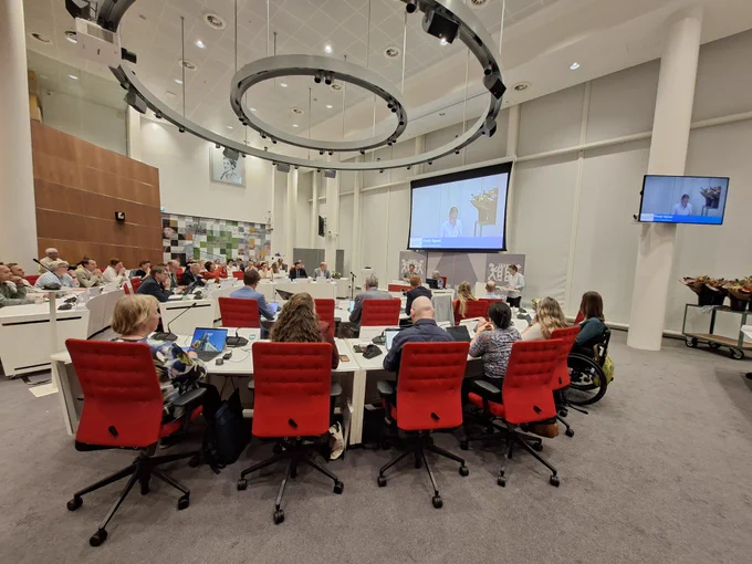 Foto van de raadzaal in het Huis van de Stad met junior stadsdichter Puck Spoel achter het spreekgestoelte