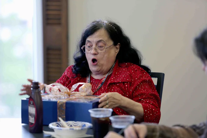 Pictured is a photo of U T A Libraries staff member Donna Kelley opening a gift at her retirement party.
