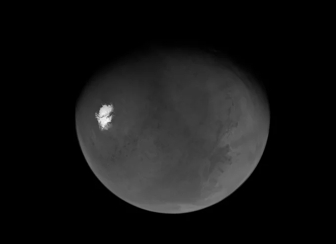 A photo of Mars, partially shadowed toward the top of the image, from its south polar region. The planet appears gray from this angle, and its southern ice cap is stark white by contrast. Credit: NASA/JPL-Caltech/ASU