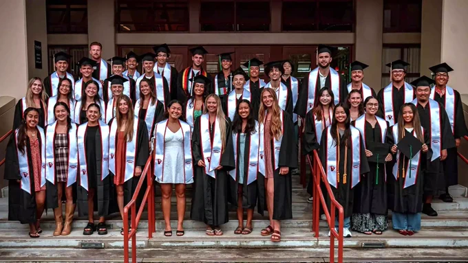 Spring 2026 Vulcan student-athlete graduating cohort, all in commencement regalia, each with white sash. (Photo: Athletics/UH Hilo)