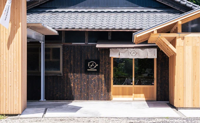 

岐阜のせんべい屋田の中屋の店舗外観。焼き杉の黒い壁と新しい木材のコントラスト、瓦屋根、白い暖簾が映える里山の佇まい。