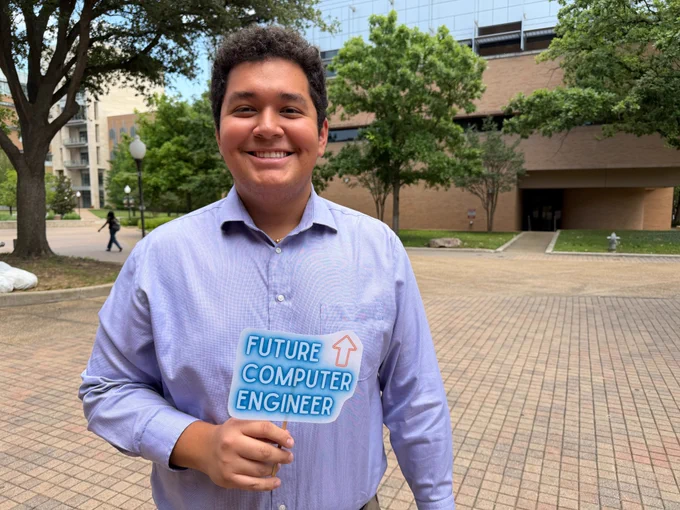 a man smiles while holding a sign that reads "future computer engineer"
