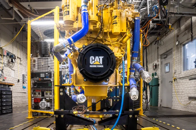 A large Caterpillar (CAT) Marine Power engine is displayed in a well-lit industrial workshop. 