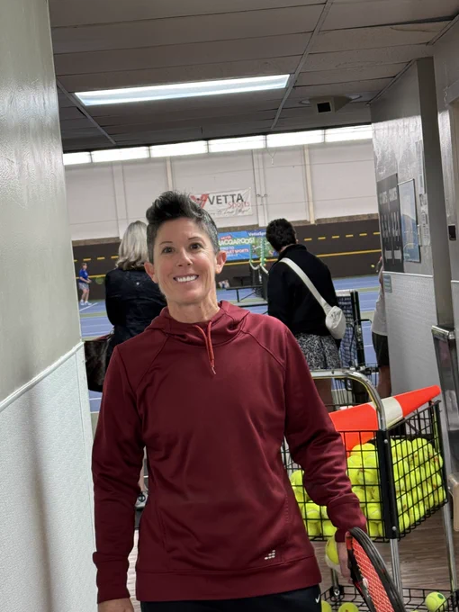 Lindsay Smith smiling with a basket of tennis balls and a traffic cone behind her