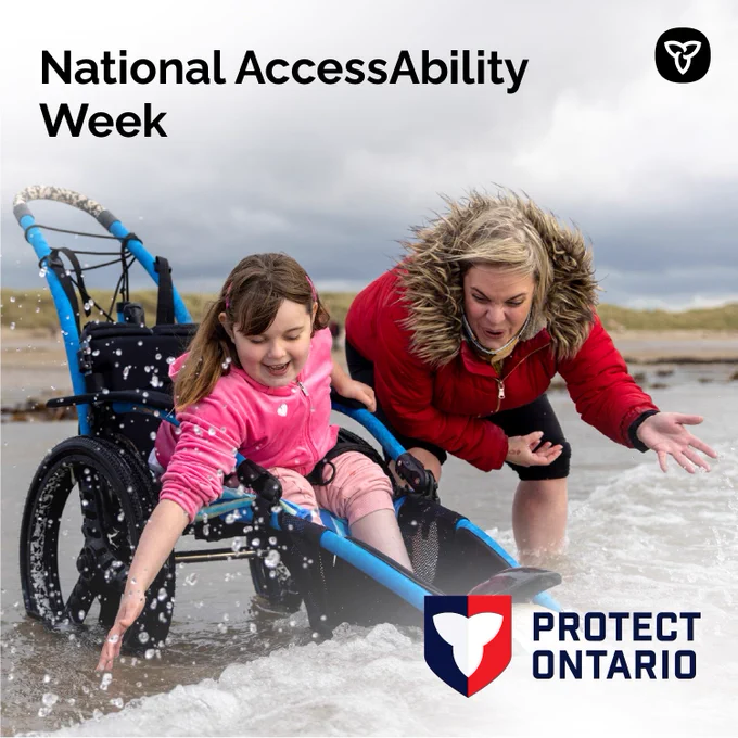 A child in a wheelchair and another person playing in the water at a beach. Text reads: National AccessAbility Week