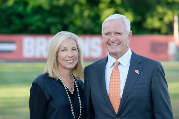 Dee Haslam and Jimmy Haslam standing together and smiling outdoors in front of a blurred background.