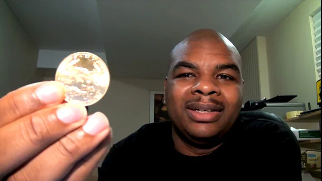 DaVinci Jeremie holding a gold Bitcoin coin, the OG bitcoiner who urged everyone to buy just $1 worth of BTC in 2013.