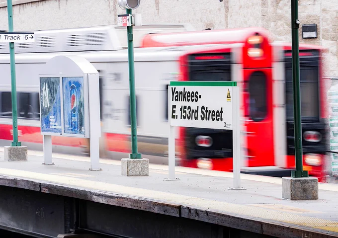 A Metro-North New Haven Line train pulling into Yankees-E. 153rd Street station during the daytime.