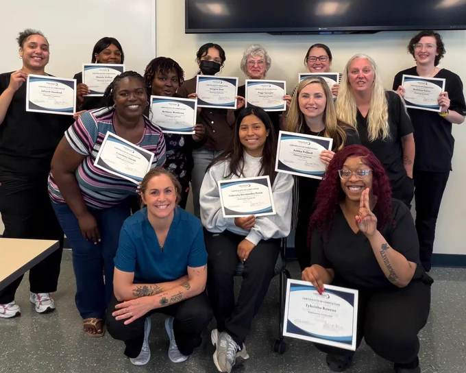June 2026 Phlebotomy Technicians cohort holding their certificates, with their instructor