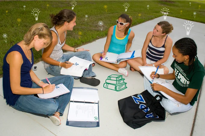 a photo of people sitting on a lawn while studying with books in their laps