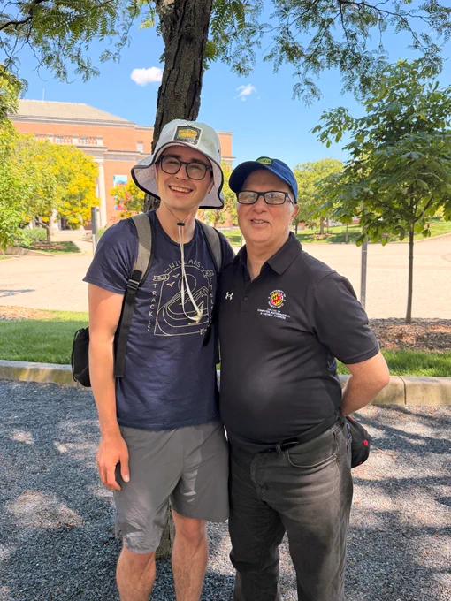 Two people standing next to each other in front of an outdoor plaza