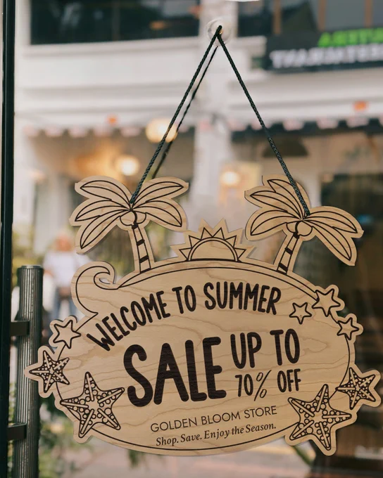 Custom Laser Cut Cherry Wood Sign With Beach Artwork Shape And Engraved With Summer Sale Details Mounted On Glass Window