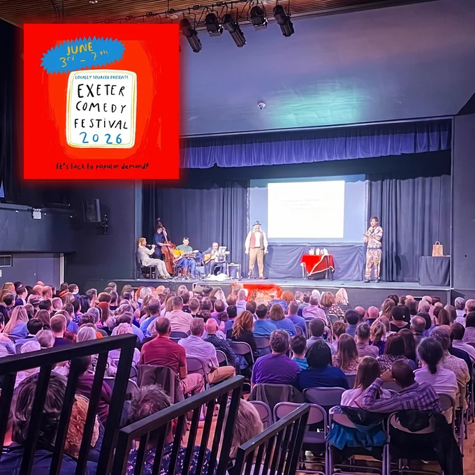 Large audience seated in a theatre watching a comedy performance on stage. Several performers and musicians are under bright stage lights, with a projected screen behind them. An inset poster in the top-left corner reads: “Locally Sourced Presents Exeter Comedy Festival 2026, June 3rd–7th. It’s back by popular demand!”