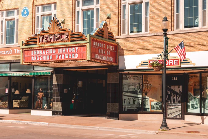 A restored theater marquee reading “Temple” projects over a historic downtown sidewalk, with messages about embracing history and imagination displayed on the sign.