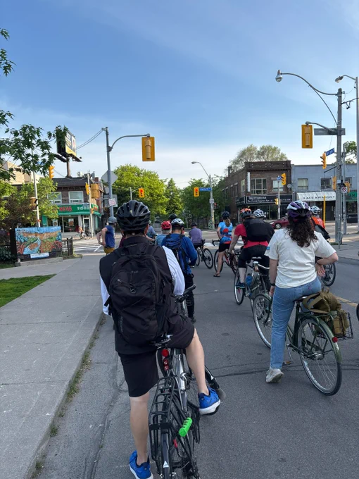 Group of cyclists wearing helmets riding through a city street at a red light on Bike to Work Day.