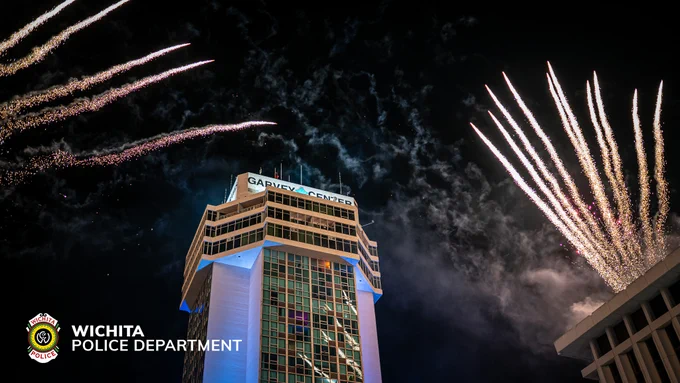 Fireworks illuminate the night sky above the illuminated Garvey Center building. The Wichita Police Department logo is visible in the bottom left corner.
