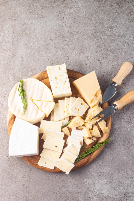 Assorted cheeses on a wooden board.
