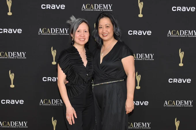 Two women standing on red carpet. 