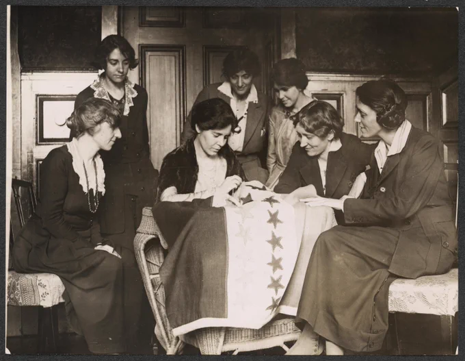 National Woman's Party activists watch Alice Paul sew a star onto the NWP Ratification Flag. 1920. Photo by the National Photo Company. National Women's Party Records, Library of Congress.
