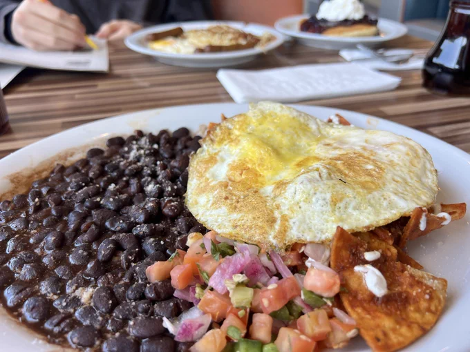 Plates of food at a diner while someone in the background fills out a sample ballot.