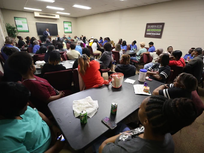 Large gathering of school custodians in meeting room.