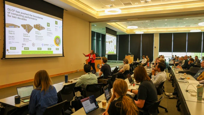 Ashley Barker speaking into a handheld microphone while presenting to attendees during the Oak Ridge Leadership Computing Facility Annual User Summit at Oak Ridge National Laboratory. 