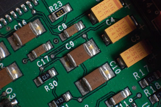 Close-up photo of several brown multilayer ceramic capacitors soldered onto a green printed circuit board, with nearby resistor and reference labels visible.