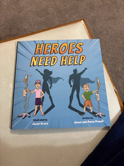 A light blue picture book cover depicts two children holding IV poles. Their shadows are superheroes.