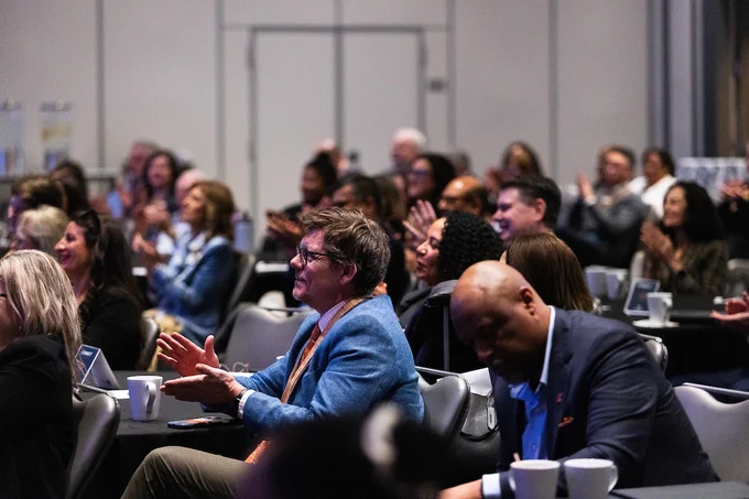 Audience members seated in a conference room, attentively listening and engaging during a presentation or panel discussion.