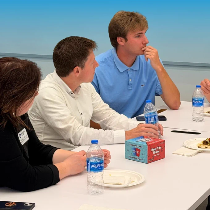Guest speaker Colin Hodge sitting with Summer Founders Program teams at a table. 