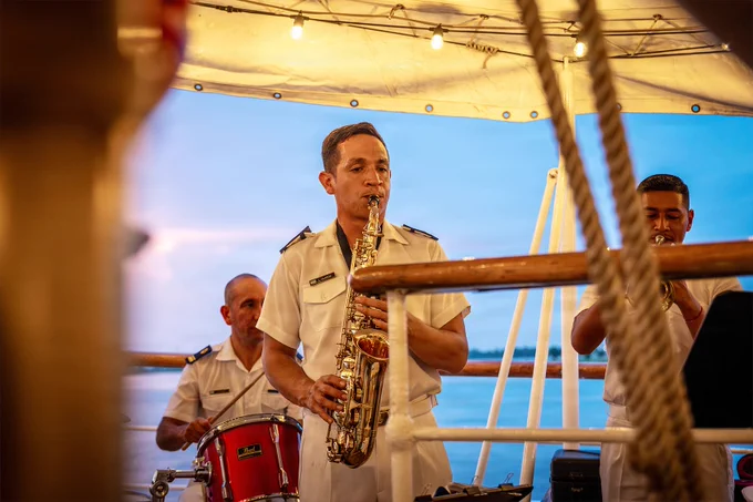 Chilean navy band perform live music aboard a tall ship during an evening reception while guests gather on deck.