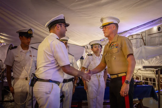A U.S. Marine officer shakes hands with a Chilean naval officer aboard a tall ship during a formal maritime engagement while sailors stand in formation nearby.